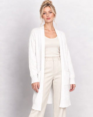a blonde model against a white background wearing a cream and white outfit. 