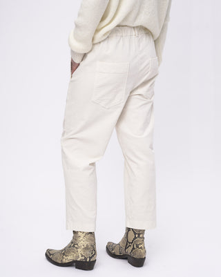 Person wearing white pants and patterned boots on a white background