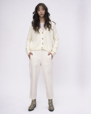 Person wearing a cream-colored cardigan and pants on a white background