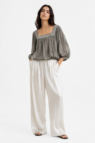 Woman wearing a gray blouse and white pants on a white background
