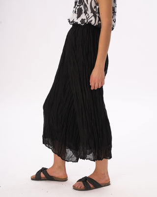 Person wearing a black pleated skirt on a white background