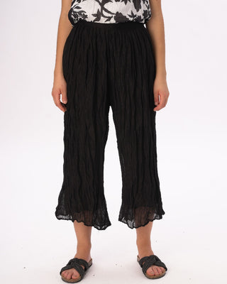 Person wearing black ruffled pants on a white background