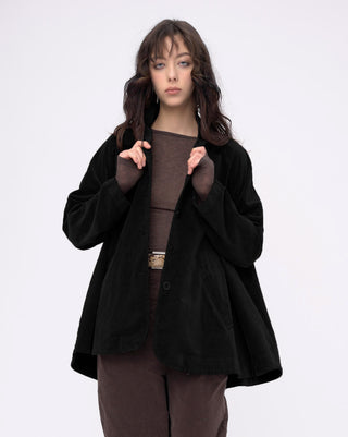 Woman wearing a black coat over a brown outfit on a white background