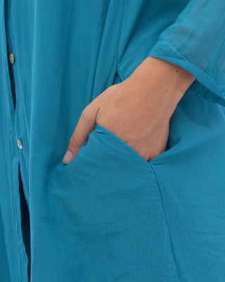 a close up view of a blue shirt with a model's hand in her pocket