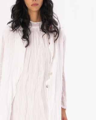 Woman wearing a white long-sleeve dress with buttons on a white background