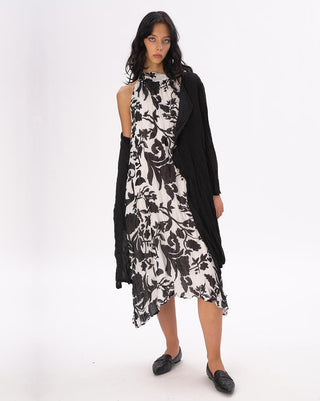 Woman wearing a black and white floral dress with a black cardigan on a white background
