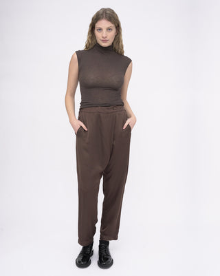 Woman wearing a brown sleeveless top and high-waisted pants on a white background