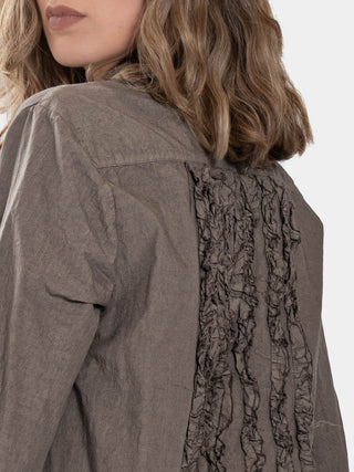 a model in a brown colored outfit standing against a white background