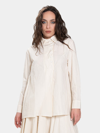 a model in a cream colored outfit with brown hair standing against a white background