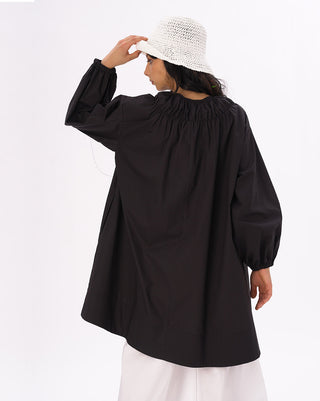 a model standing against a white background with a white hat and a black and white outfit on. 