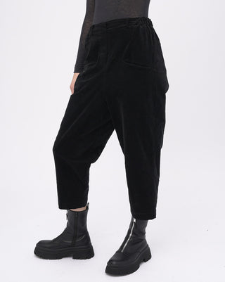 Black velvet pants worn by a person on a white background