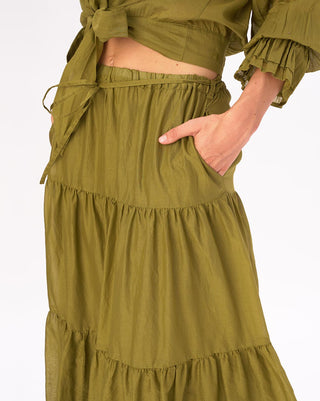 A green pleated tiered cotton skirt with a tie waist, worn by a model.