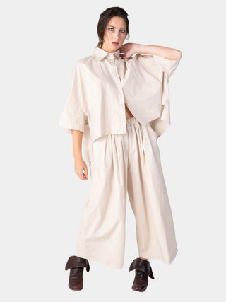 A woman wearing a beige Hi-Lo Organic Cotton Cropped Shirt with a collar, front pocket, and a loose fit.