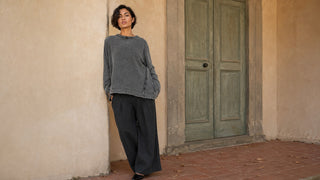 a model standing outside with a pewter grey sweater on and dark grey pants. 