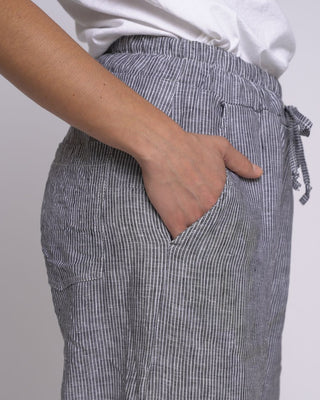 Person wearing gray striped pants with a white shirt on a plain background