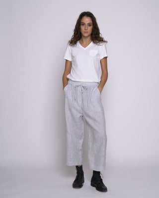 Woman wearing a white t-shirt and light gray pants against a white background
