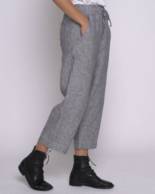 Person wearing gray checkered pants and black boots on a white background
