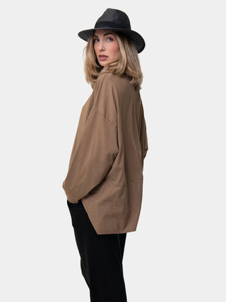 a model wearing a hat and a brown and black outfit against a white wall