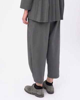 Person wearing a gray outfit with wide-leg pants on a white background