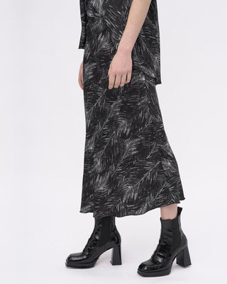 Person wearing a black and white patterned dress with black boots on a white background