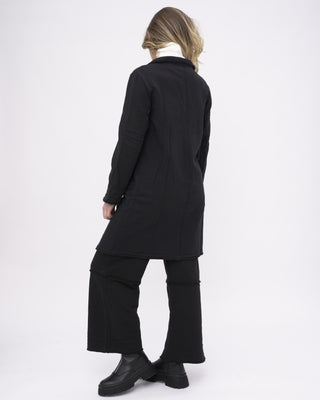 a model dressed in all black against a white background with her back facing the camera