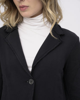 close up of a models chest to show the fabric details of a black overcoat and white turtle neck
