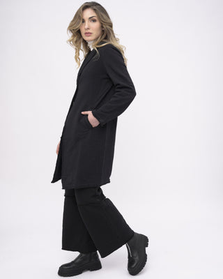 a model dressed in all black walking against a white background from her side view