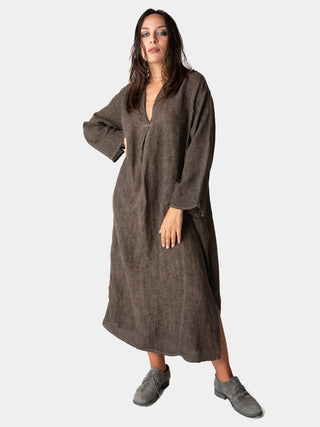 a model wearing a long brown dress standing against a white background