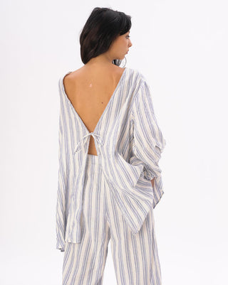 a model wearing a light blue and white striped outfit against a white background