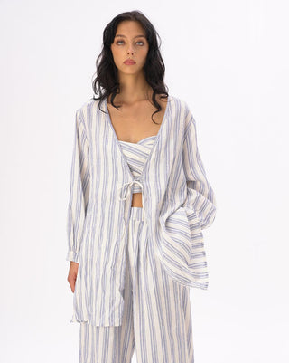 a model wearing a light blue and white striped outfit against a white background
