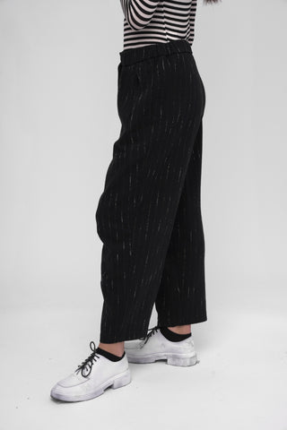 Person wearing black pants with white stripes and white sneakers on a white background