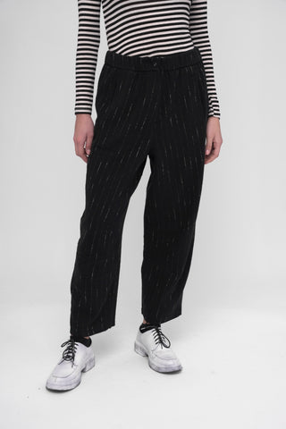 Person wearing black striped shirt and black pants with white dots on a white background