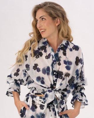 A woman wearing a tie waist button up shirt with a watercolor small floral pattern.