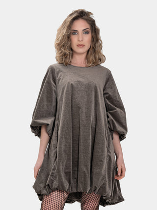 a model wearing a brown balloon dress in front of a white studio background