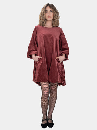 Woman wearing a rust-colored dress with long sleeves on a white background