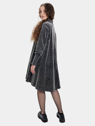 a woman wearing a blue grey velvet dress against a white background
