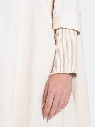 a close up of a cream fabric showing ribbed detailing and a models hand