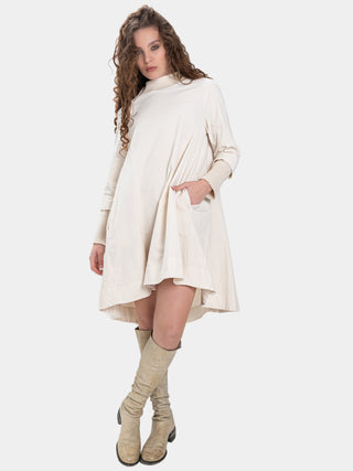 a woman wearing a cream colored dress and boots against a white background