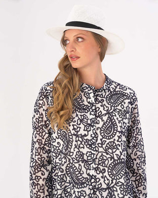 Woman wearing a white dress with black pattern and a white hat on a white background