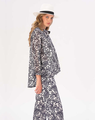 Woman wearing a black and white patterned outfit with a hat on a white background