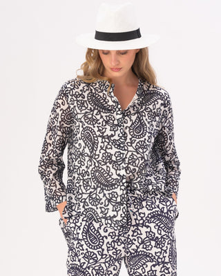 Woman wearing a black and white patterned outfit with a white hat on a light gray background