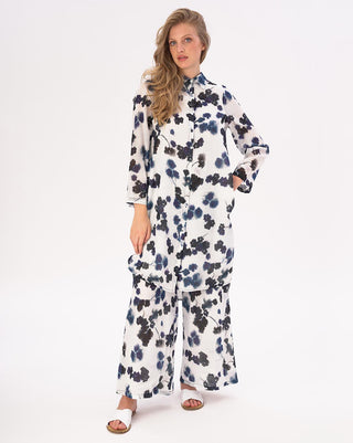 A woman modeling a white hi-lo floral button shirtdress with long sleeves and side slits.