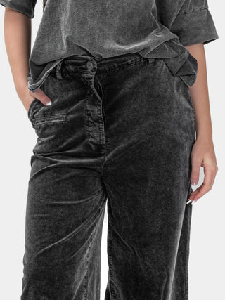 Person wearing dark gray pants and a matching top on a white background