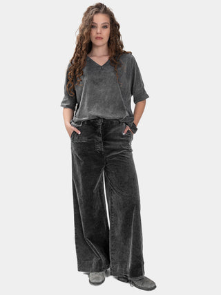 Woman wearing a gray top and wide-leg jeans on a white background