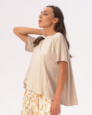 Woman wearing a beige top and patterned skirt on a white background