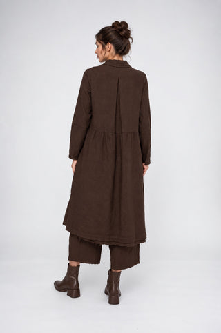 a brunette model wearing an all brown outfit against a grey white background.