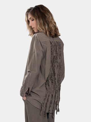 a model in a brown colored outfit standing against a white background