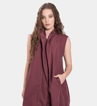 Woman wearing a sleeveless burgundy blouse on a white background