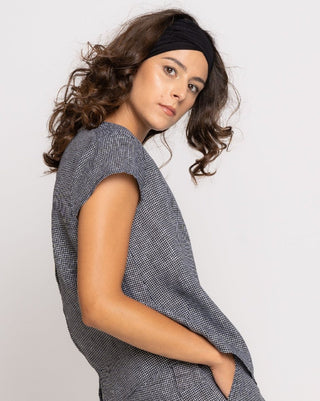 Woman wearing a gray sleeveless top against a white background