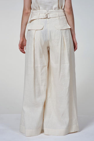 Person wearing a white outfit with wide-leg pants on a plain background